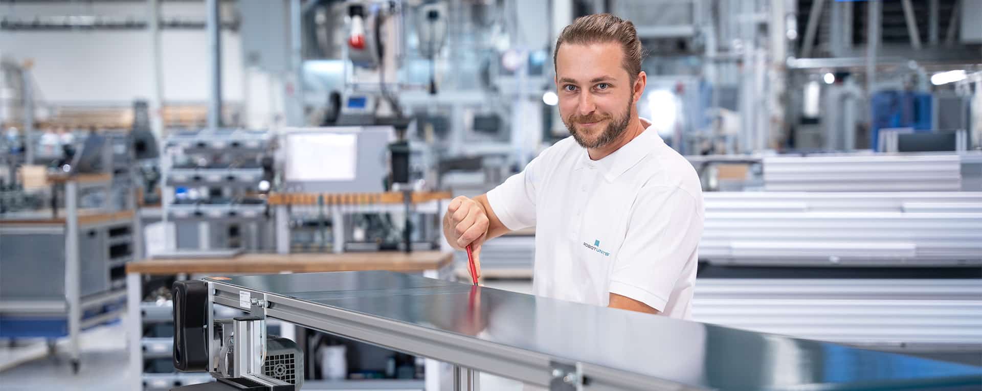 Ein Robotunits Mitarbeiter montiert ein Gurtförderband in einer Montagehalle zusammen.